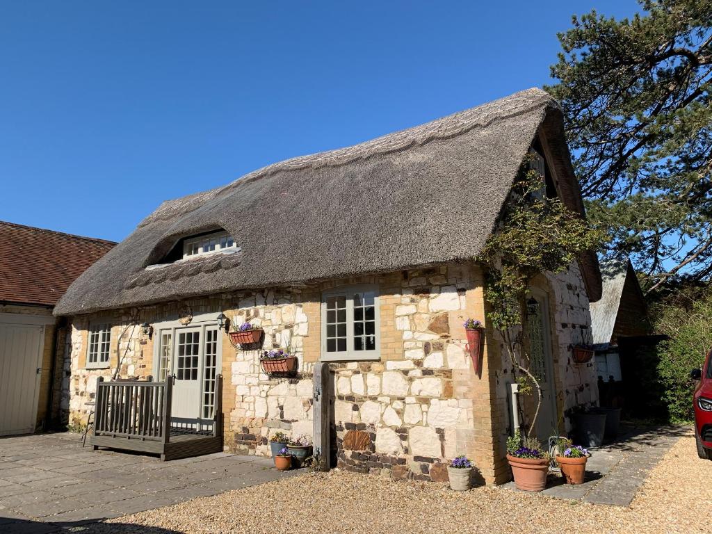 an old stone building with a thatched roof at Brixton Barn in Mottistone
