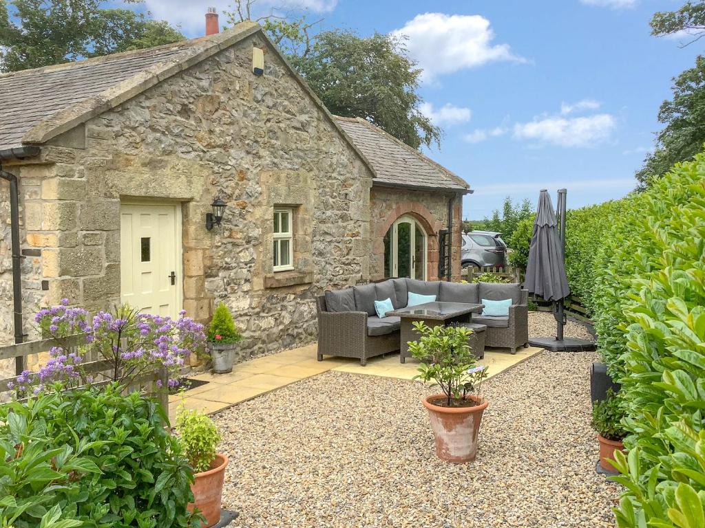 a stone cottage with a couch and a table in a yard at Cloggy Nook Tughall in Swinhoe