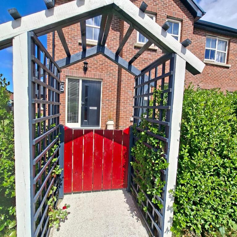 a red gate in front of a brick house at Semos in Strabane