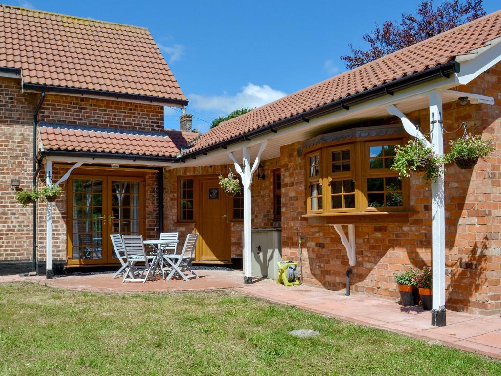 a brick house with chairs and a table on a patio at Boothby Cottage in Willoughby