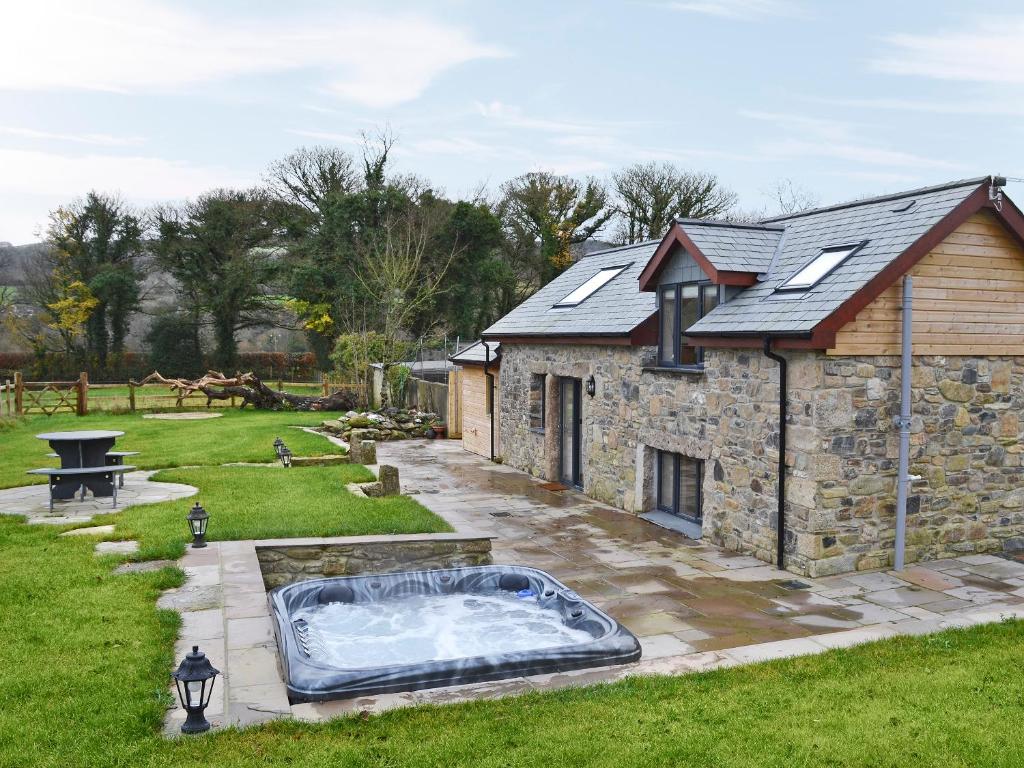 a stone building with a hot tub in the yard at Bluebell Barn in Okehampton