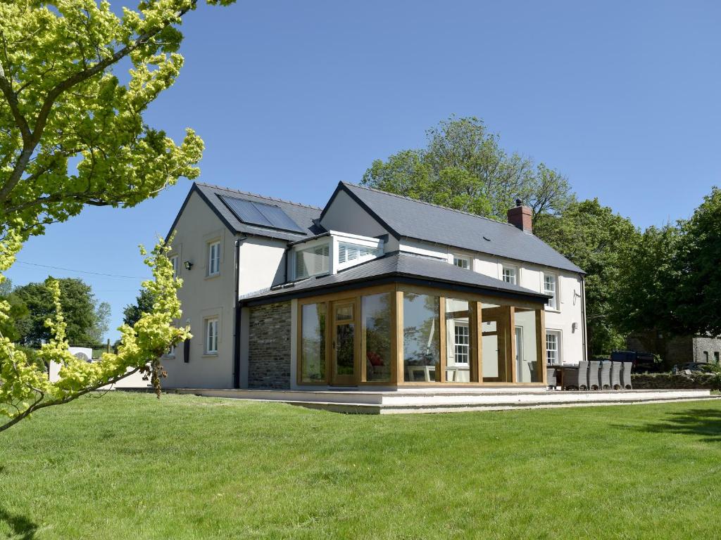 a house with a conservatory on a lawn at Fountain Hill in Eglwyswrw