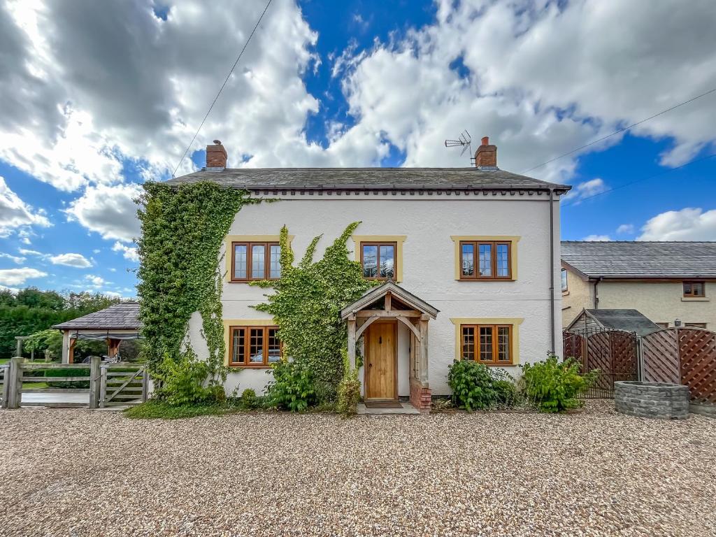 a white house with ivy on the side of it at Pant Ifan Goch in St Asaph