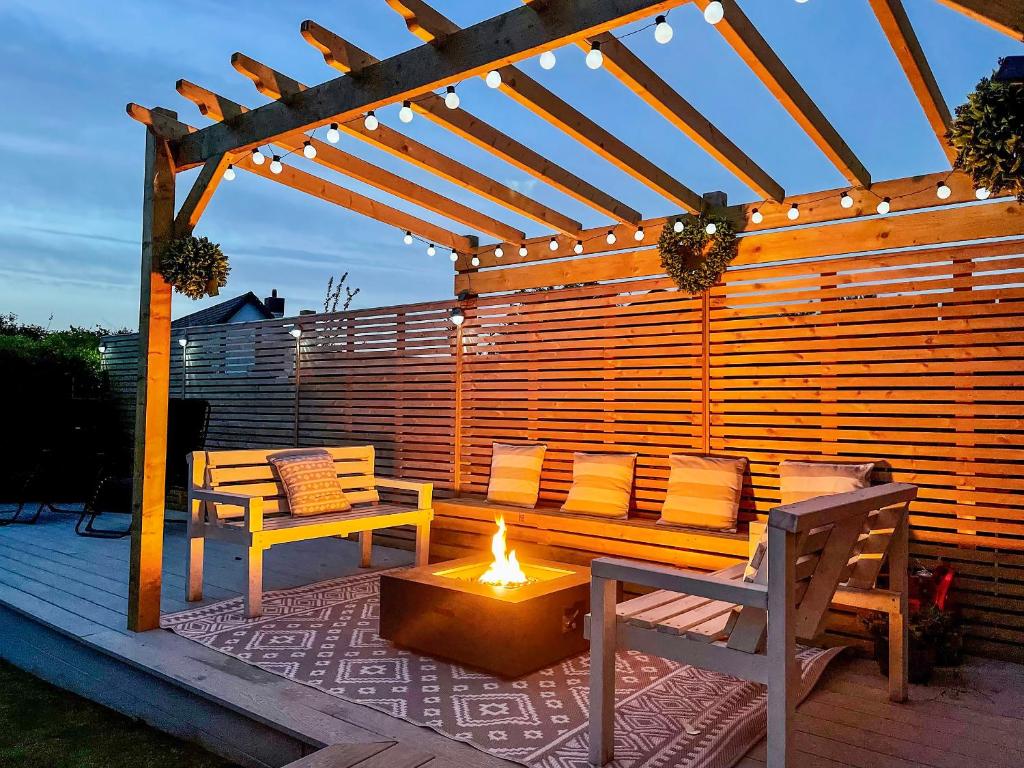 a wooden pergola with two chairs and a fire pit at Llwyn Ysgaw in Cemaes Bay