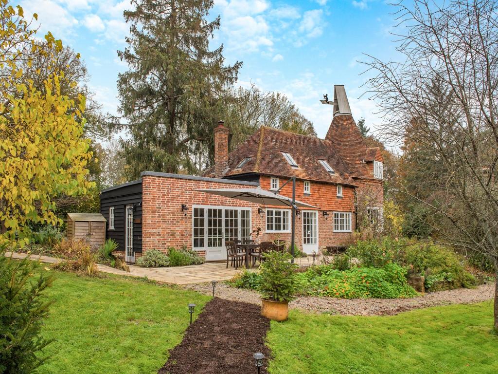 an old brick house with a patio in a yard at Mousehall Oast in Wadhurst