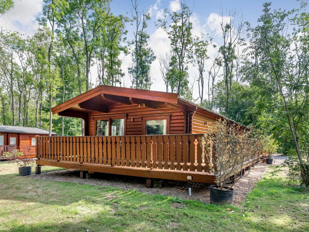 a cabin in the woods with a large deck at Cherry Lodge- Uk37608 in Legbourne