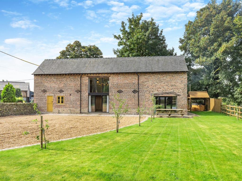 a brick house with a large lawn in front of it at Shepherds Barn in Bollington