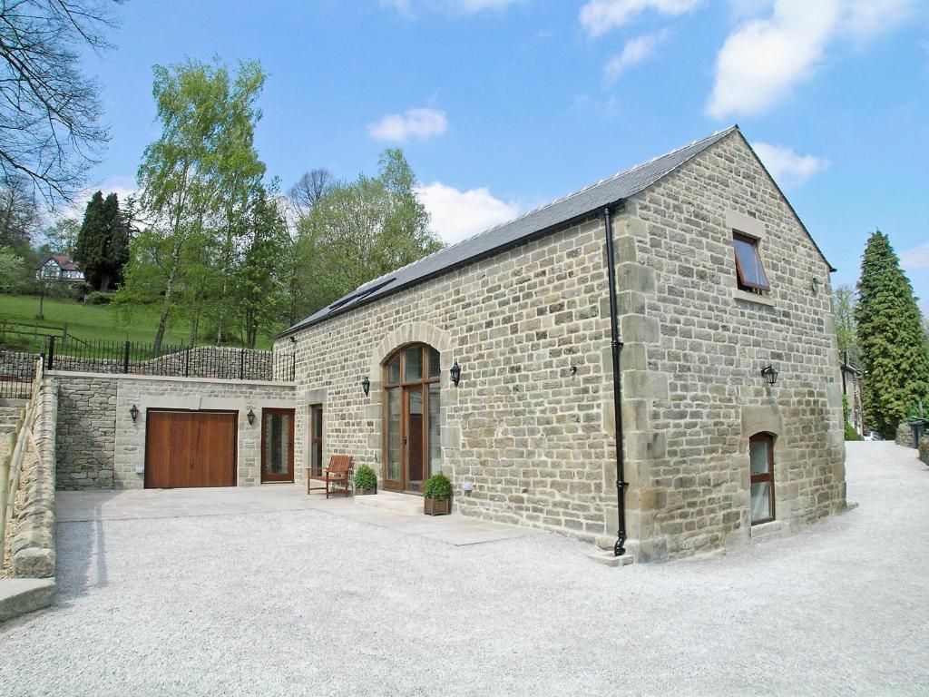 a large brick building with a wooden door at Tythe Barn in Froggatt