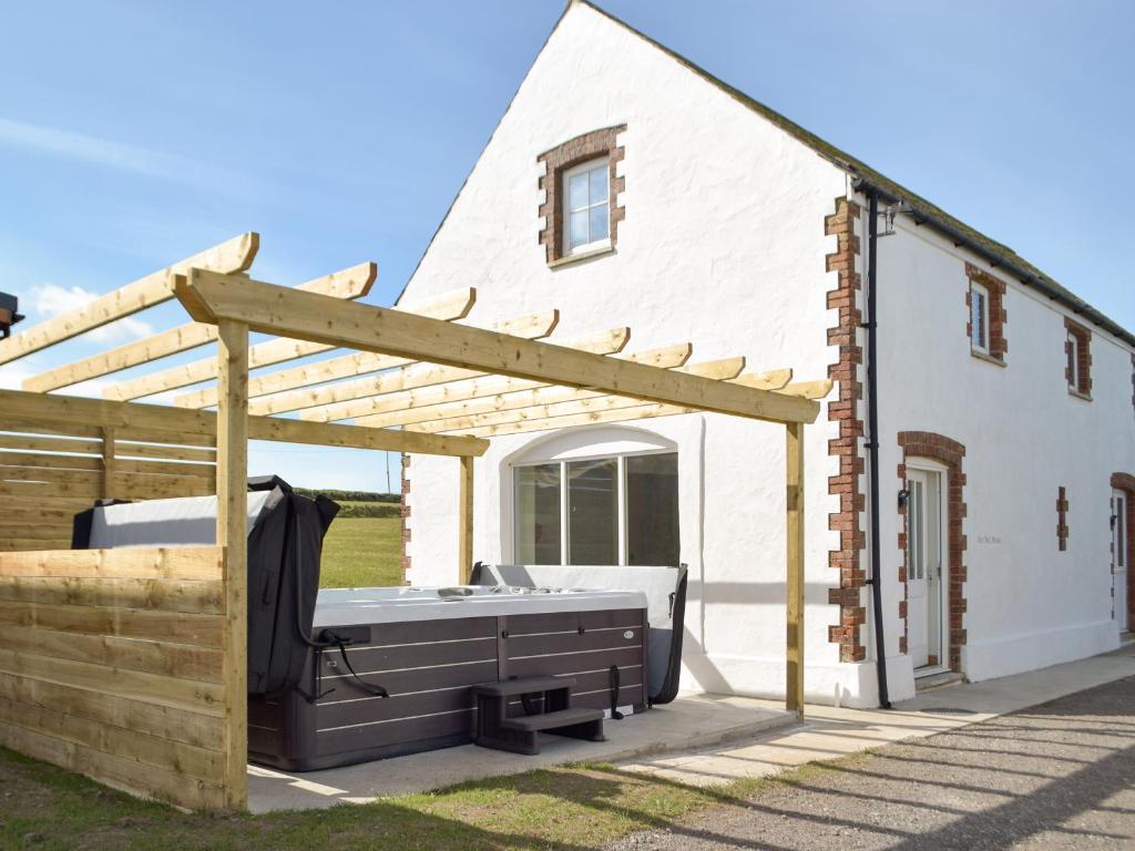 a hot tub under a pergola next to a house at The Millhouse - Uk32510 in Marloes