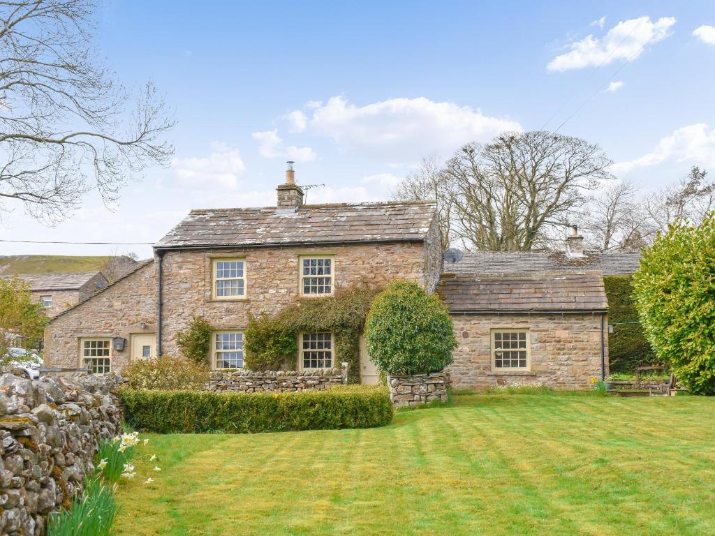 an old stone house with a large yard at Alpine Cottage in Carperby