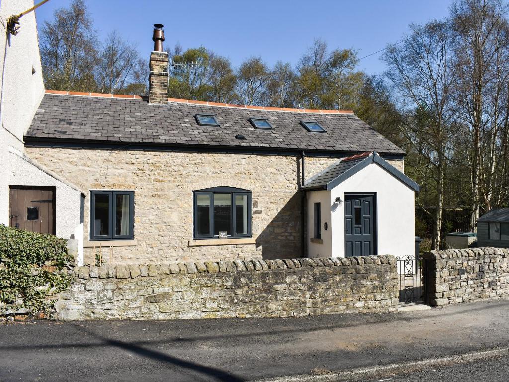 a stone house with a stone wall and a door at Rose Cottage in Bardon Mill