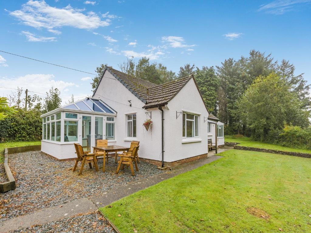 a white cottage with a table and chairs at Pine Cottage - Uk46874 in Hartland