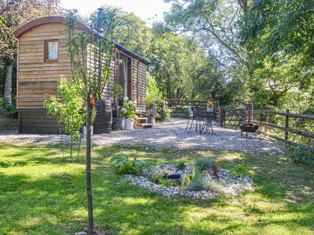 a small cabin with a table and chairs in a yard at Herdwick Hut Mountain Retreat in Twyn Llanan