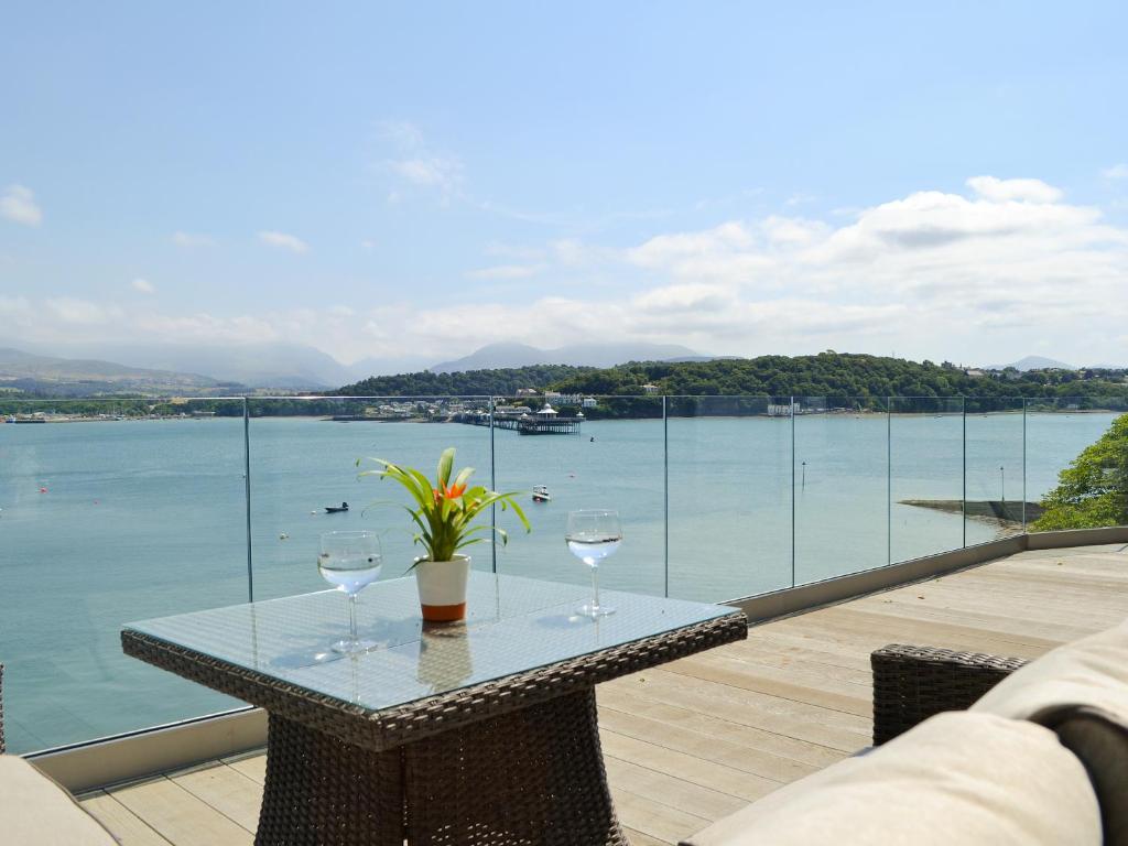 a table with two wine glasses and a view of the water at Tan Y Fford in Bangor