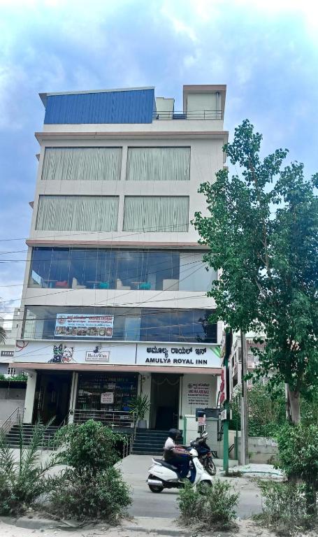 a building with a motorcycle parked in front of it at Hotel Amulya Royal Inn in Bangalore