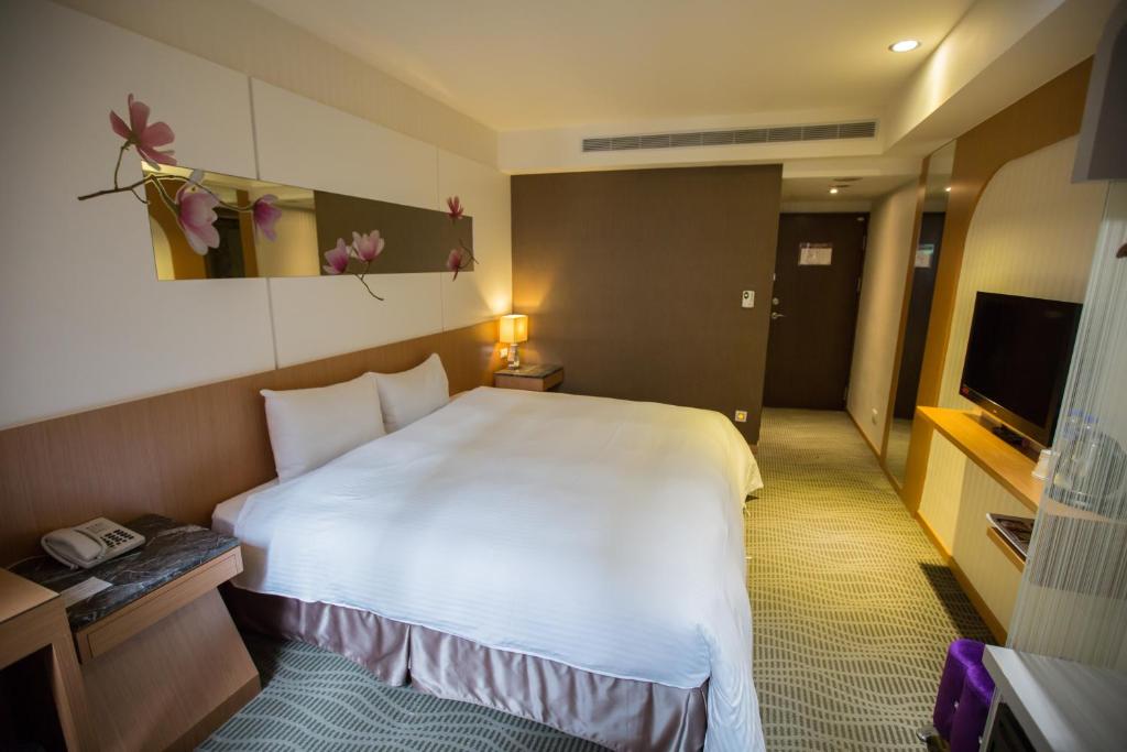 a hotel room with a large white bed and a television at Ximen Relite Hotel in Taipei