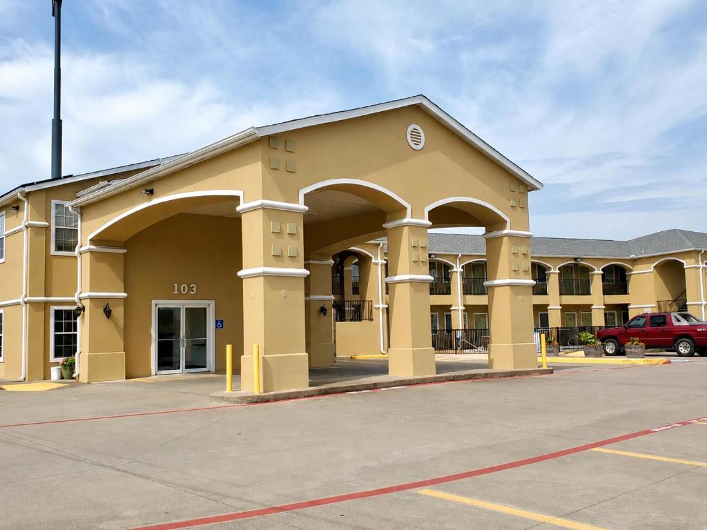 an empty parking lot in front of a building at Scottish Inns & Suites Forney in Forney