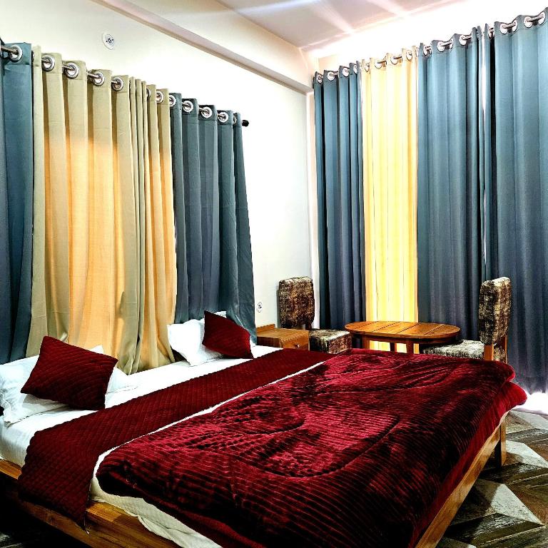 a bedroom with a large bed with blue curtains at Hotal DESPRADES MRITYUNJAY INN in Jageshwar