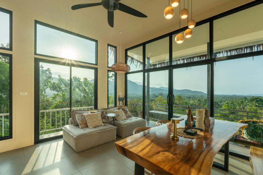 a living room with a table and some windows at Archie Paradise View in Thong Sala