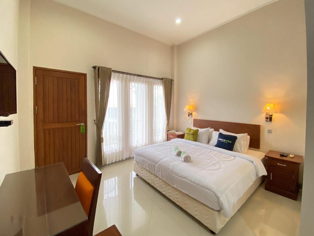 a bedroom with a large white bed and a table at Urbanview Hotel Ratna Syariah in Sukobumi