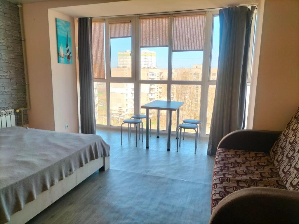 a bedroom with a table and chairs and a large window at Морской дом in Odesa