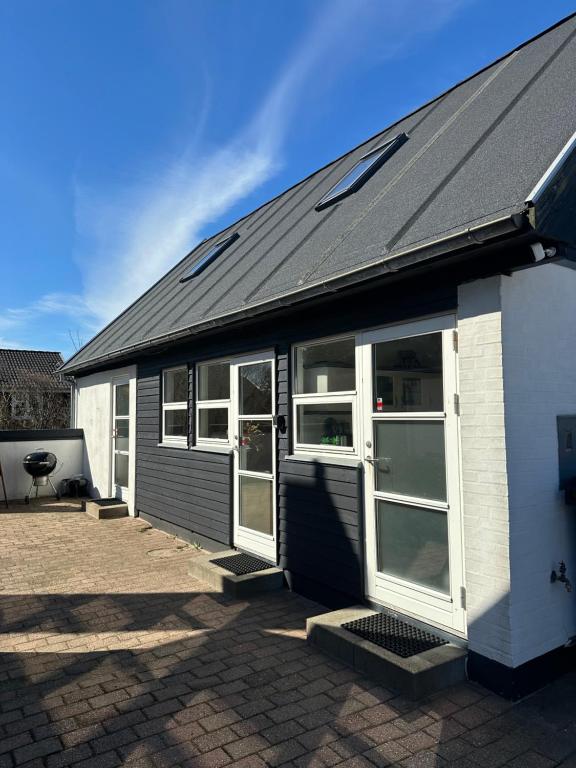a building with white doors and a black roof at Guesthouse Villa Sønderklit in Skagen
