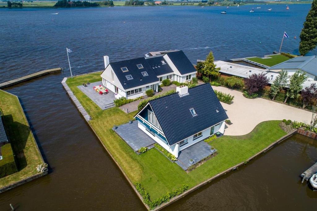 an aerial view of a house on an island in the water at Villa Verderop - Luxury Lakeside Villa with Terrace & Water Views in Friesland in Boornzwaag