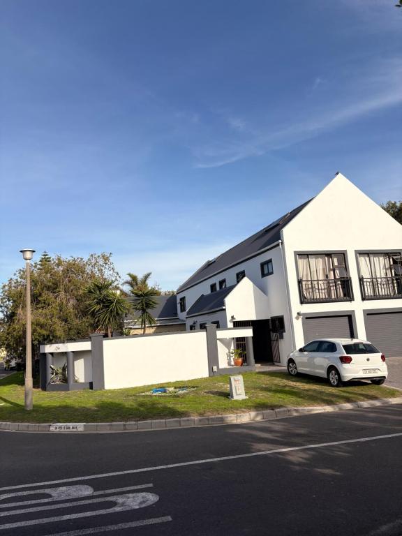 a white house with a car parked in front of it at Saint's Inn in Parklands