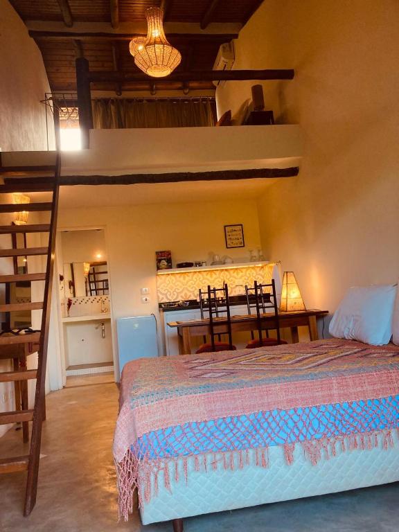 a bedroom with a bed and a table with chairs at Flats Bon Voyage Caboré - Chez Cira in Paraty