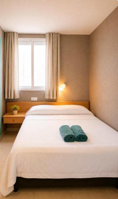 a bedroom with a white bed with two towels on it at Pensión Jordi Tossa de Mar in Tossa de Mar