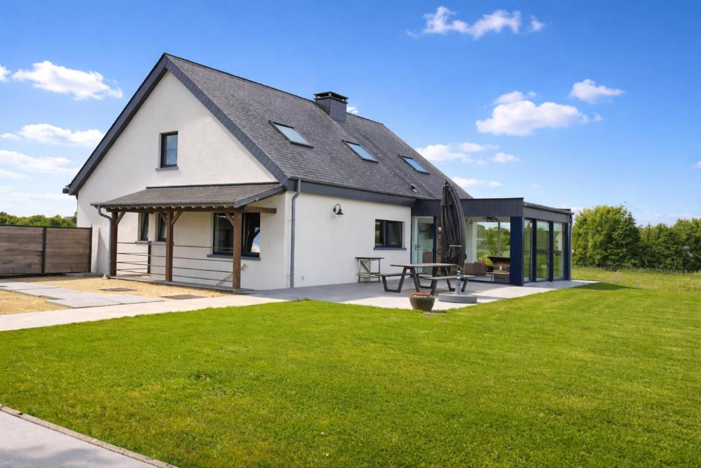 ein weißes Haus mit schwarzem Dach und einem Hof in der Unterkunft Villa Intensity in Bastogne