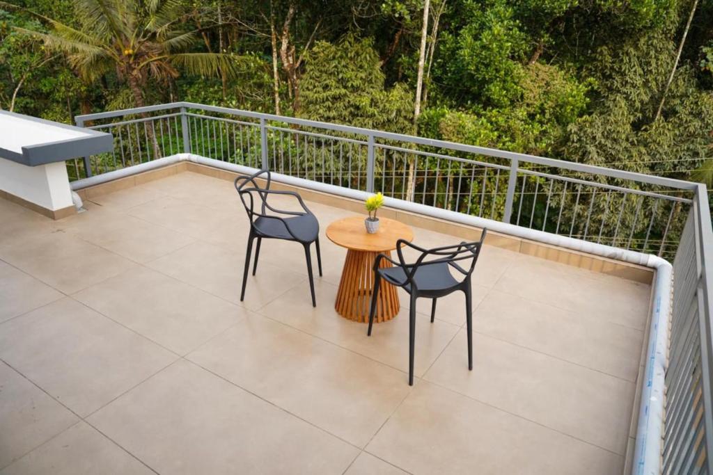 a patio with two chairs and a table on a balcony at SafeStay Wayanad - 1BHK & 2BHK with Kitchen Facilities in Wayanad