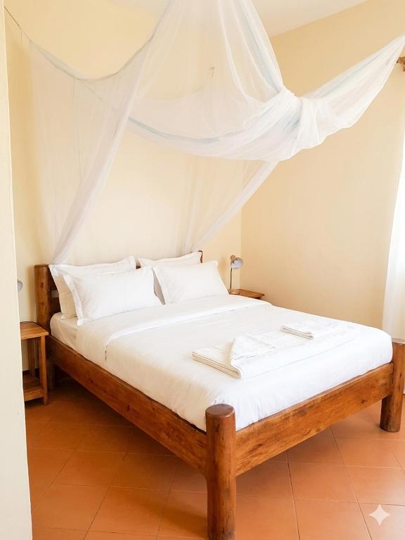 a bed with white sheets and pillows in a room at Yasipi Cottages in Sipi