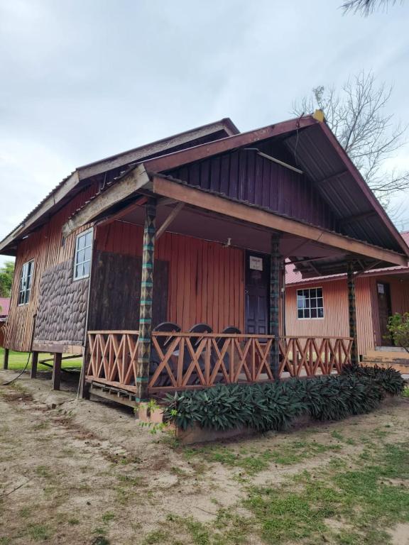 a wooden house with a porch with chairs on it at CBR Beach in Kota Belud