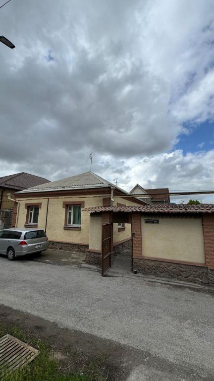 a house with a car parked in front of it at Aruzhan Hostel in Shymkent