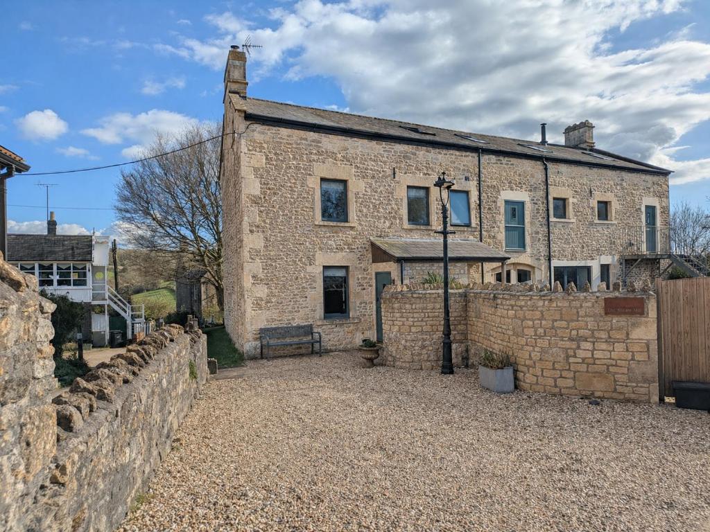 a stone house with a brick wall and a fence at Steam Mill in Wellow