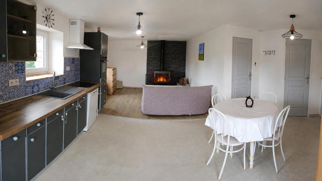 a kitchen with a table and chairs and a fireplace at Le Logis du Commis in Notre-Dame-dʼElle
