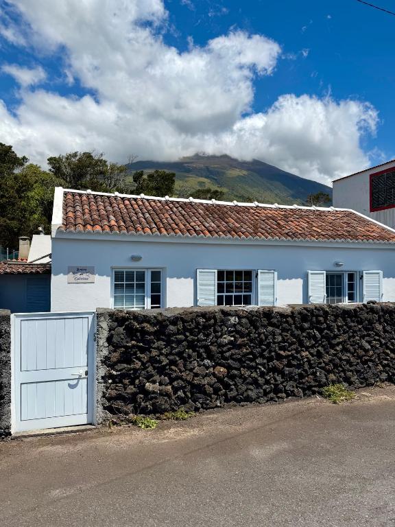 a white house with a stone wall and a fence at Retiro dos Cabritos in São Mateus