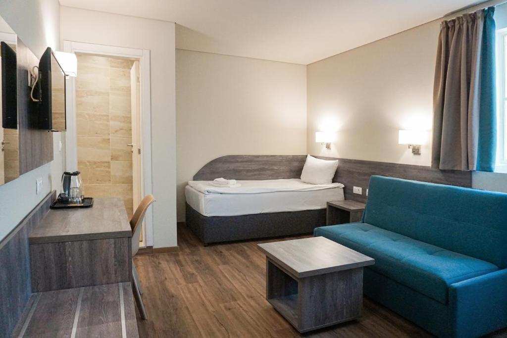 a hotel room with a bed and a blue couch at Terminal Park in Bischofsheim