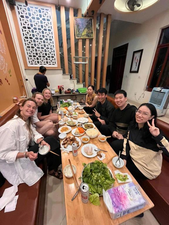 a group of people sitting around a table with food at NinhBinh Central Homestay l Green Path in Xuân Sơn
