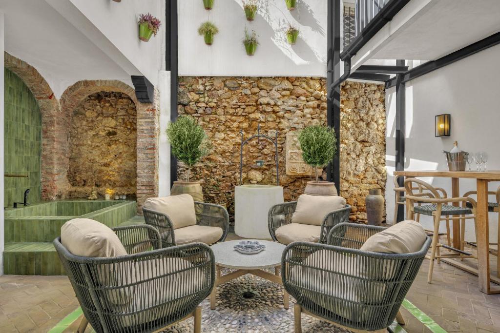 a room with chairs and a table and a stone wall at Casa Azalia - Marbella Old Town by Finest Rentals in Marbella