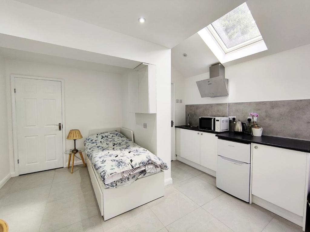a white kitchen with a bed and a sink at New Studio Near Science Park Cambridge in Cambridge
