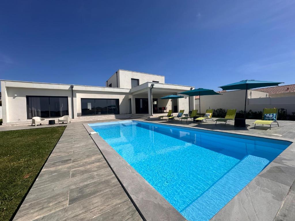 a swimming pool in front of a house at Spacieuse villa standing de 220m2 à 5 minutes des plages in Aléria