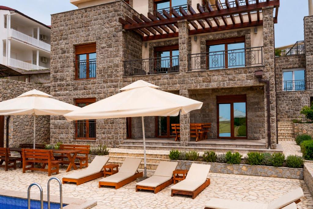 a villa with a swimming pool and patio with umbrellas at Villa Vitanika in Kunjići