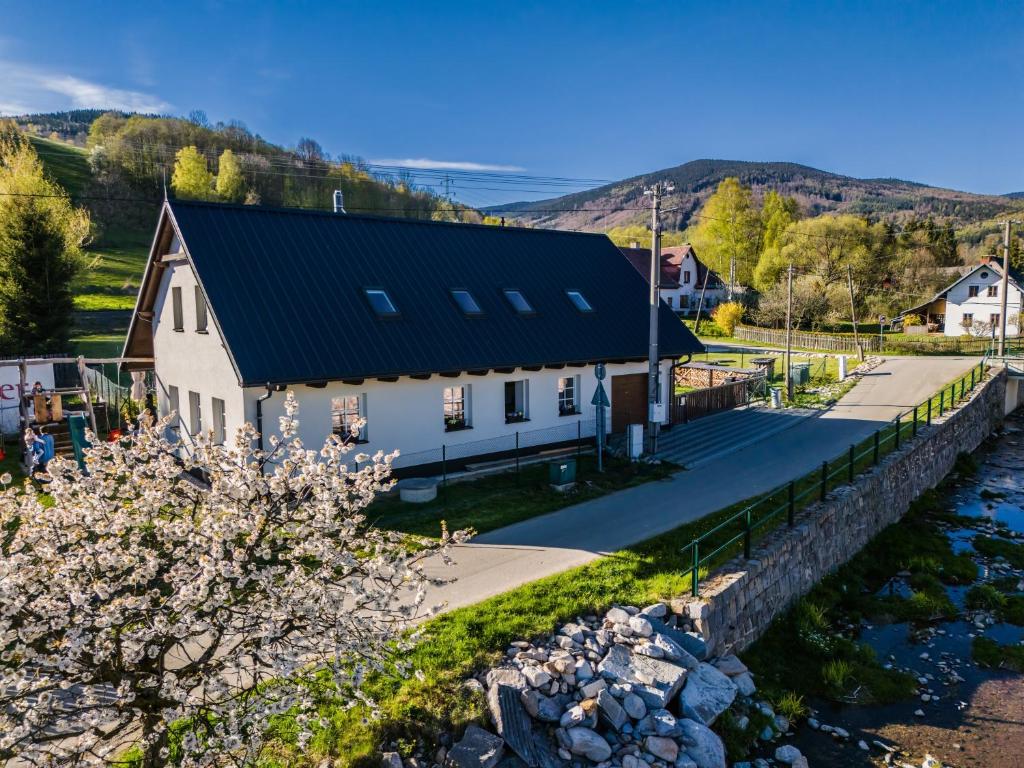 a white house with a black roof next to a river at Chalupa Rébus in Loučná nad Desnou