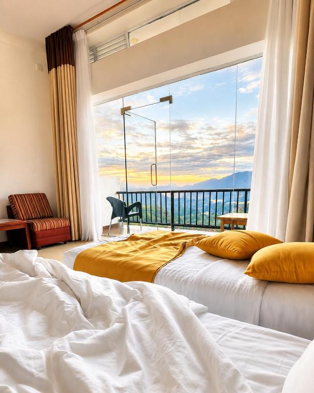 two beds in a room with a large window at Thuruliya Hotel in Ramboda