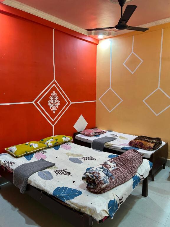 two beds in a room with red walls at Snehalata Lodge in Badarpur