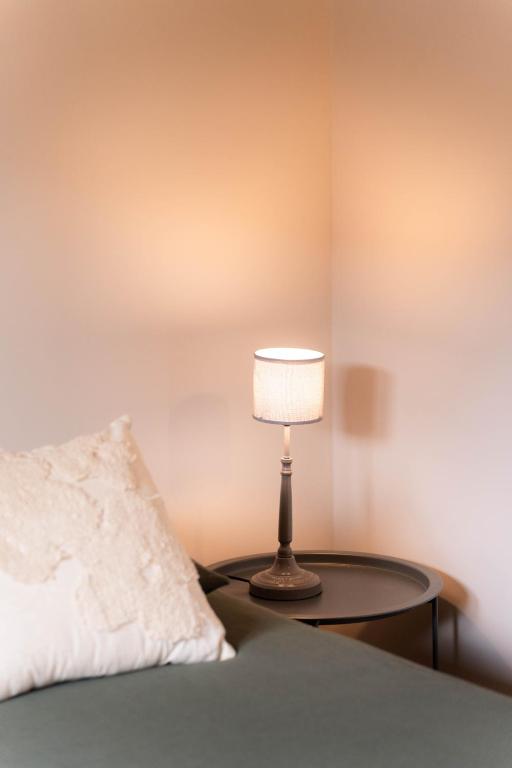 a lamp sitting on a table next to a bed at Jasmin et Camomille in Roquebrun