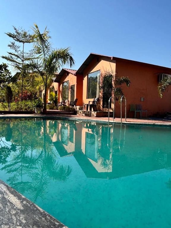 a swimming pool in front of a house at Earavat Resort in Rāmnagar