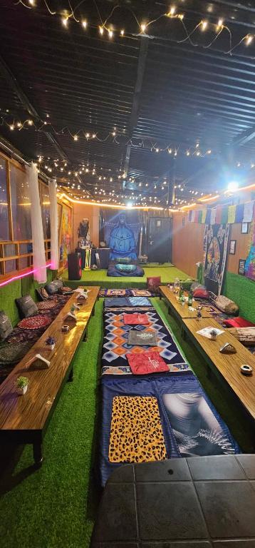 a room with long wooden tables and green carpet at Kasol Shalom Camps & Cafe in Kasol